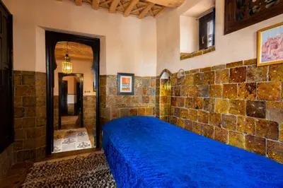 a bedroom with a blue bed in a brick wall at Hôtel Riad Dar Daïf in Ouarzazate