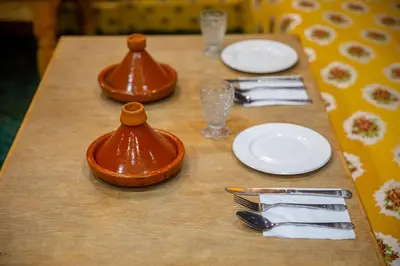 a wooden table with plates and utensils on it at Riad Eloria Fes in Fès