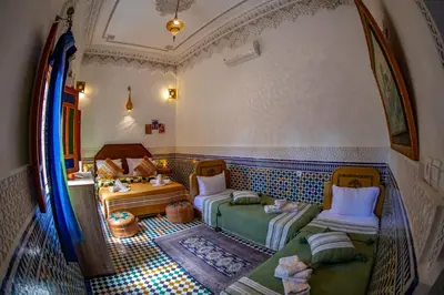 an attic room with two beds and a table at Riad Eloria Fes in Fès