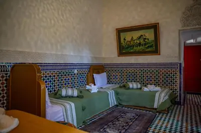 a room with two beds and a painting on the wall at Riad Eloria Fes in Fès
