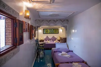 a room with two beds and a table in it at Riad Eloria Fes in Fès