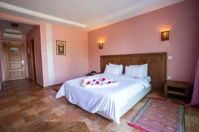 a bedroom with a large white bed with flowers on it at Hotel Dar Eddaya in Khemisset