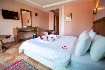 a bedroom with a bed with red flowers on it at Hotel Dar Eddaya in Khemisset