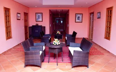 a dining room with pink walls and chairs and a table at Hotel Dar Eddaya in Khemisset