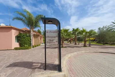 a sign on a brick street with palm trees at Hotel Dar Eddaya in Khemisset