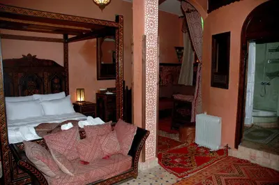 a bedroom with a bed and a couch and a mirror at Riad Lahboul in Meknès