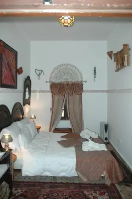 a bedroom with a white bed and a window at Riad Lahboul in Meknès