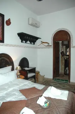 a bedroom with a bed and a piano and a mirror at Riad Lahboul in Meknès
