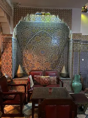 a living room with a couch and a large wall at Riad Lahboul in Meknès