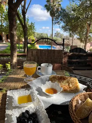 a table with a breakfast of bread and orange juice at Chez Mamouchthka in Ourika