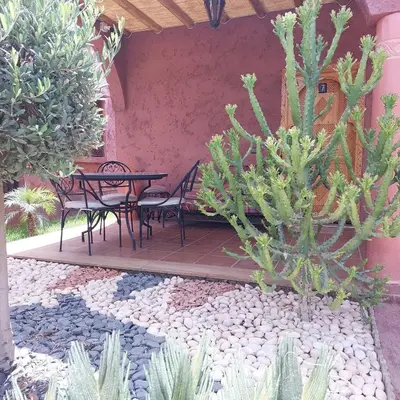 a patio with a table and chairs in a garden at Chez Mamouchthka in Ourika