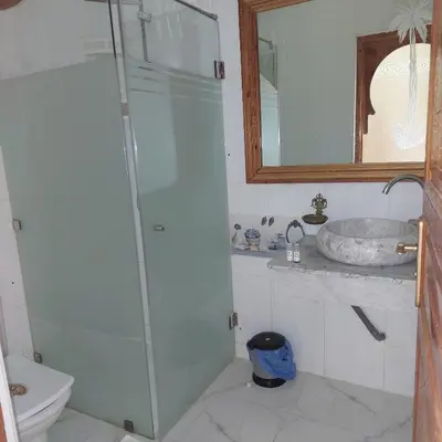 a bathroom with a glass shower and a sink at Chez Mamouchthka in Ourika