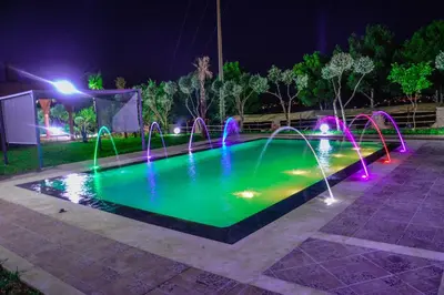 a pool with colored lights in a park at night at Chez Mamouchthka in Ourika