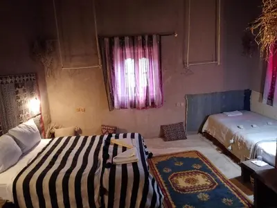 a bedroom with two beds and a rug at Kasbah Oulad Othmane in Agoubt
