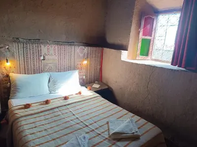 a bedroom with a bed in a room with two windows at Kasbah Oulad Othmane in Agoubt