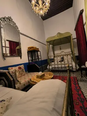 a bedroom with a bed and a couch and a mirror at Riad Lalla Zoubida in Fès