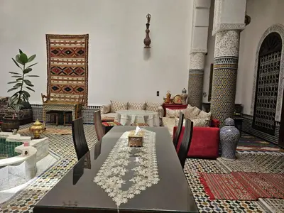 a living room with a table and chairs and a rug at Riad Lalla Zoubida in Fès