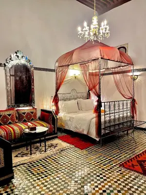 a bedroom with a canopy bed and a chandelier at Riad Lalla Zoubida in Fès