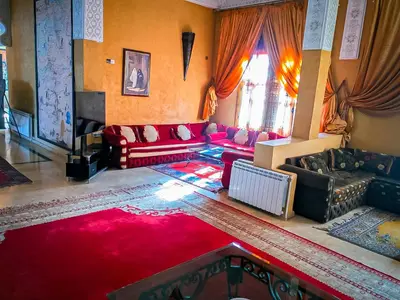 a living room with red couches and a red rug at Hotel Taddart in Midelt