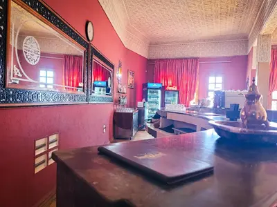 a kitchen with red walls and a table with a mirror at Hotel Taddart in Midelt