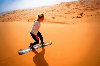 a woman walking in the desert with a skateboard at Camp Sahara Holidays in Mhamid