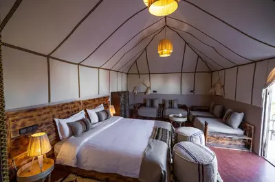 a bedroom with a bed and two chairs and a couch at DWO Golden Camp Merzouga in Merzouga