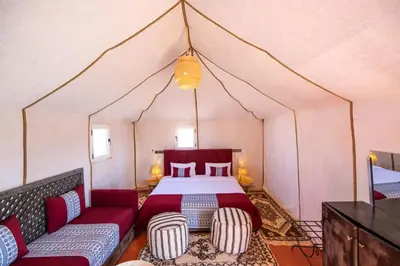 a bedroom in a tent with a bed and a couch at DWO Golden Camp Merzouga in Merzouga