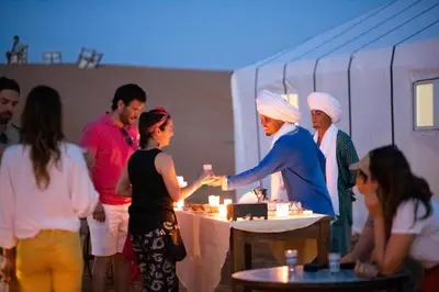 a group of people standing around a table with a cake at DWO Golden Camp Merzouga in Merzouga
