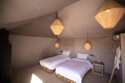 two beds in a small room with two lights at DWO Golden Camp Merzouga in Merzouga