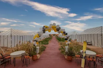 an arch with balloons and tables and chairs in a marquee at DWO Golden Camp Merzouga in Merzouga