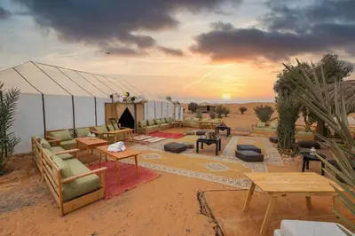a tent in the desert with couches and tables at DWO Golden Camp Merzouga in Merzouga