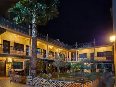 a palm tree in front of a building at night at Hotel Restaurant La Kasbah in Tinerhir