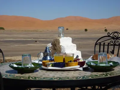 a table with food and drinks on it in the desert at Kasbah Hotel Panorama in Merzouga