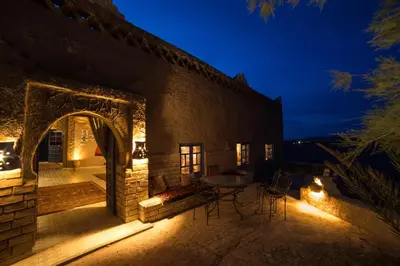 an outdoor patio with a table and chairs at night at Kasbah Hotel Panorama in Merzouga