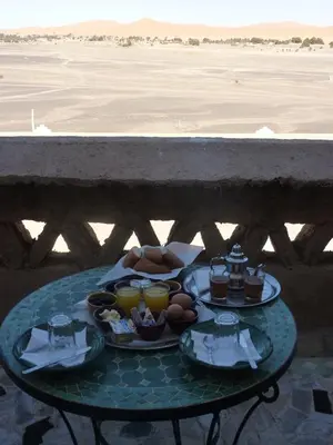 a table with plates of food on it next to a beach at Kasbah Hotel Panorama in Merzouga