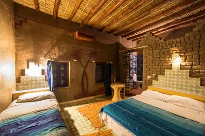 a bedroom with two beds and a stone wall at Kasbah Hotel Panorama in Merzouga