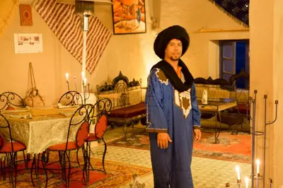 a man in a costume standing in a room with candles at Kasbah Hotel Panorama in Merzouga