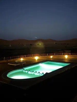 a large swimming pool at night in a desert at Kasbah Hotel Panorama in Merzouga