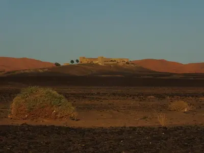 a building on a hill in the middle of a desert at Kasbah Hotel Panorama in Merzouga