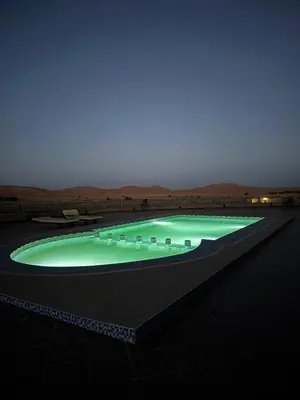a large swimming pool at night in a desert at Kasbah Hotel Panorama in Merzouga