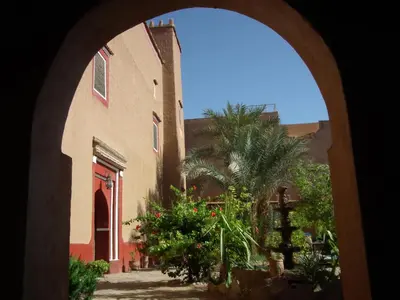 an arched doorway to a building with a palm tree at Hotel Tomboctou in Tinerhir