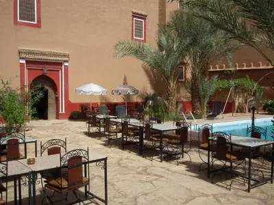 a restaurant with tables and chairs next to a pool at Hotel Tomboctou in Tinerhir