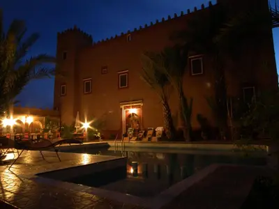 a villa with a swimming pool at night at Hotel Tomboctou in Tinerhir