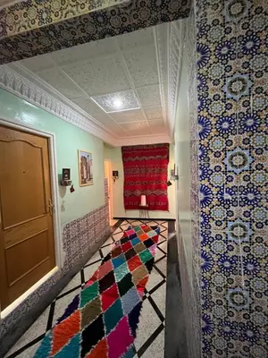 a room with a red couch and a colorful carpet at Diyar Timnay in Moulay Idriss Zerhoun