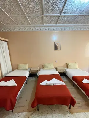 a room with three beds with red blankets at Diyar Timnay in Moulay Idriss Zerhoun