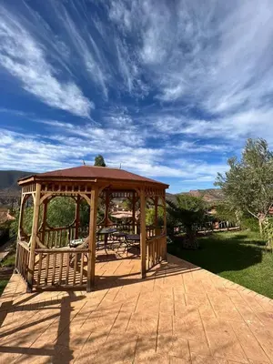 a wooden gazebo on a patio under a blue sky at Palais D'Ouzoud in Azilal