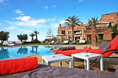 a house with a swimming pool with a red couch and tables at Kasbah Agounsane Hotel & Spa in Ourika