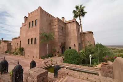 a building with a palm tree in front of it at Kasbah Agounsane Hotel & Spa in Ourika
