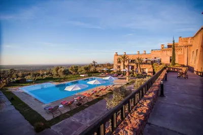a pool with chairs and umbrellas next to a building at Kasbah Agounsane Hotel & Spa in Ourika