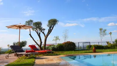 two chairs and an umbrella next to a swimming pool at Kasbah Agounsane Hotel & Spa in Ourika